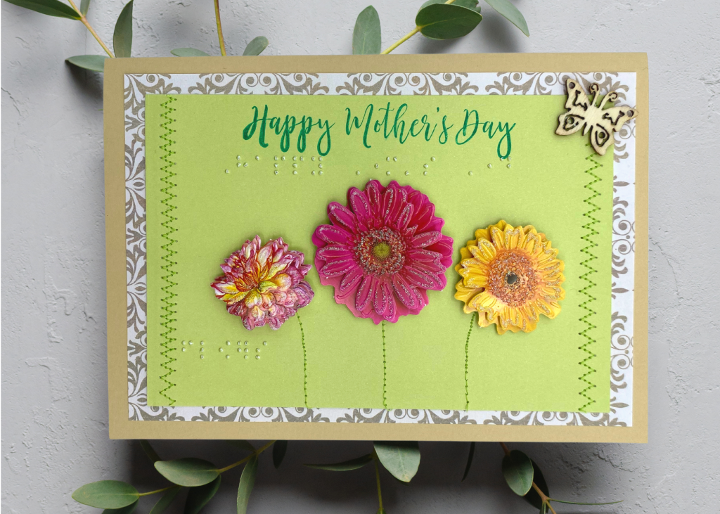 a light green card with bright spring florals which says Happy Mother's Day. the card sits on a neutral grey backdrop