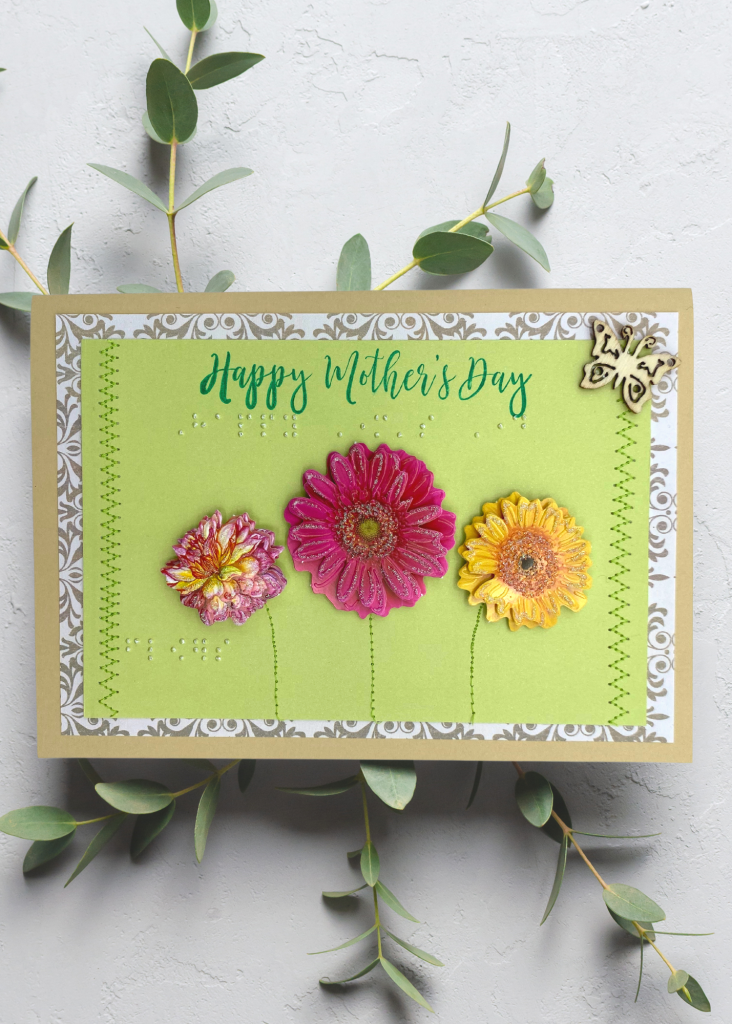 A Vibrant green card that says Happy mother's day with spring flowers on a neutral grey background
