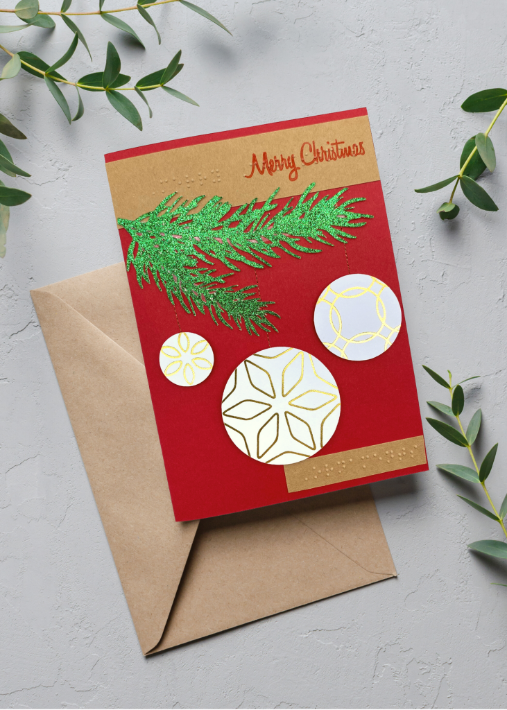 the merry christmas card sitting with a brown envelope on a neutral grey backdrop