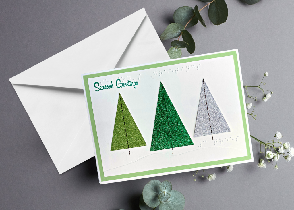 The Season's Greetings card with a white envelope on a neutral grey backdrop
