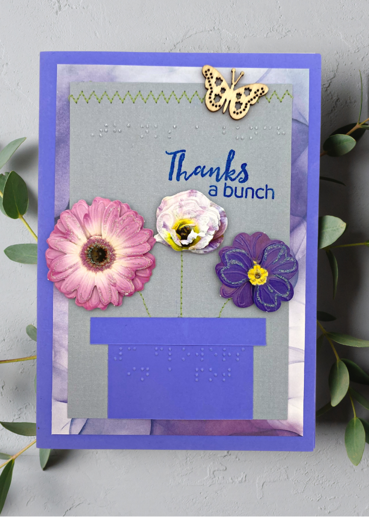 an indigo card with purple and blue florals in a pot that says thanks a bunch. The card sits on a neutral grey backdrop