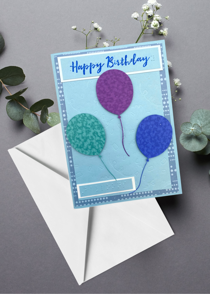 the happy birthday card sitting with a white envelope on a neutral grey backdrop