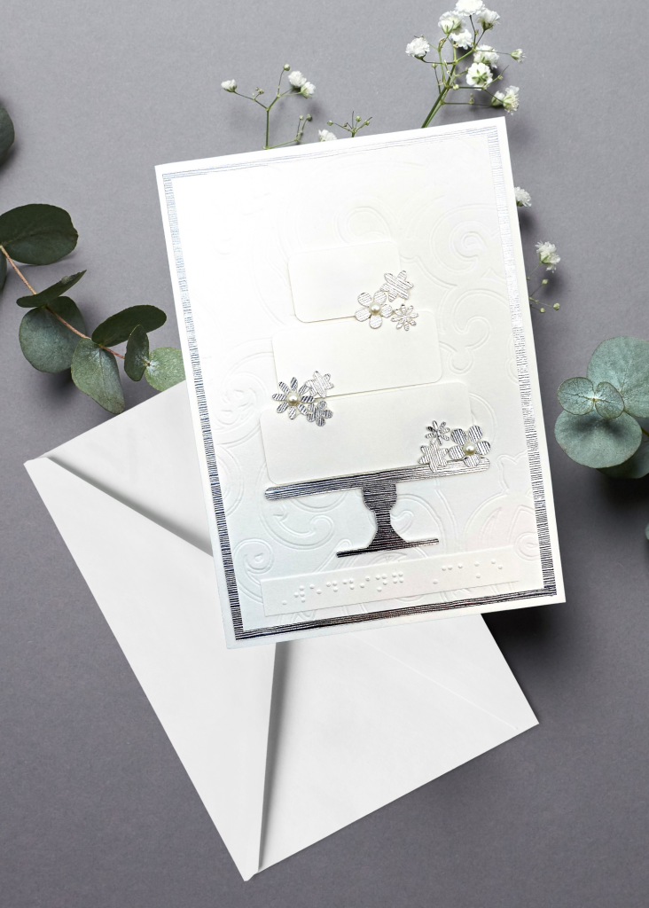 the wedding card with a white envelope on a neutral grey backdrop