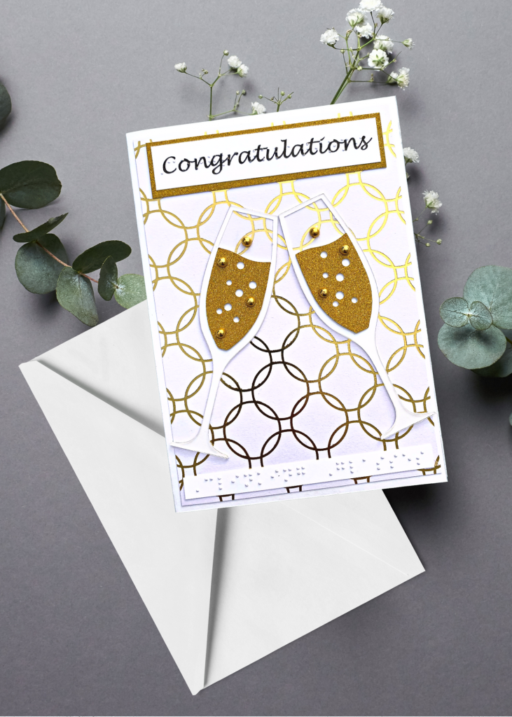 the congratulations card next to a white envelope on a neutral grey backdrop