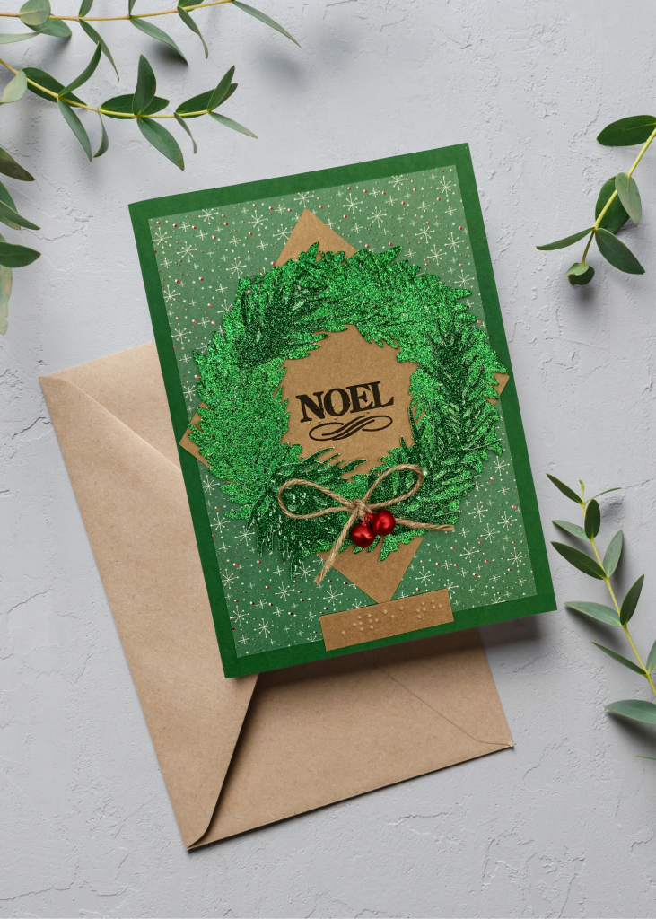 the noel card with a brown envelope sitting on a neutral grey backdrop