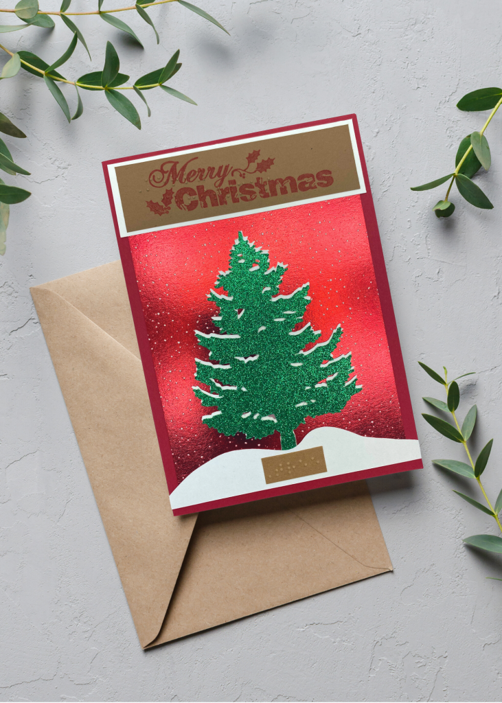 the merry christmas card sitting with a brown envelope on a neutral grey backdrop