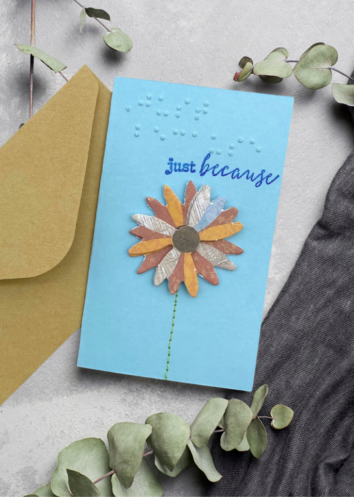 the just because card sitting with a brown envelope on a neutral grey backdrop