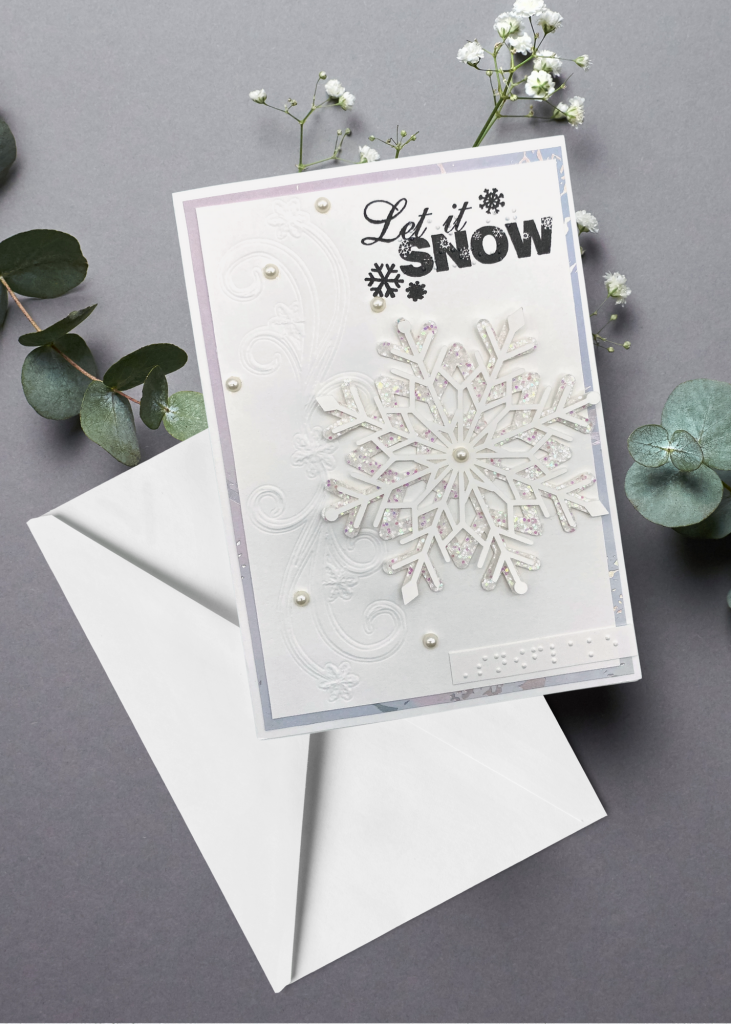 the let it snow card with a white envelope sitting on a neutral grey backdrop